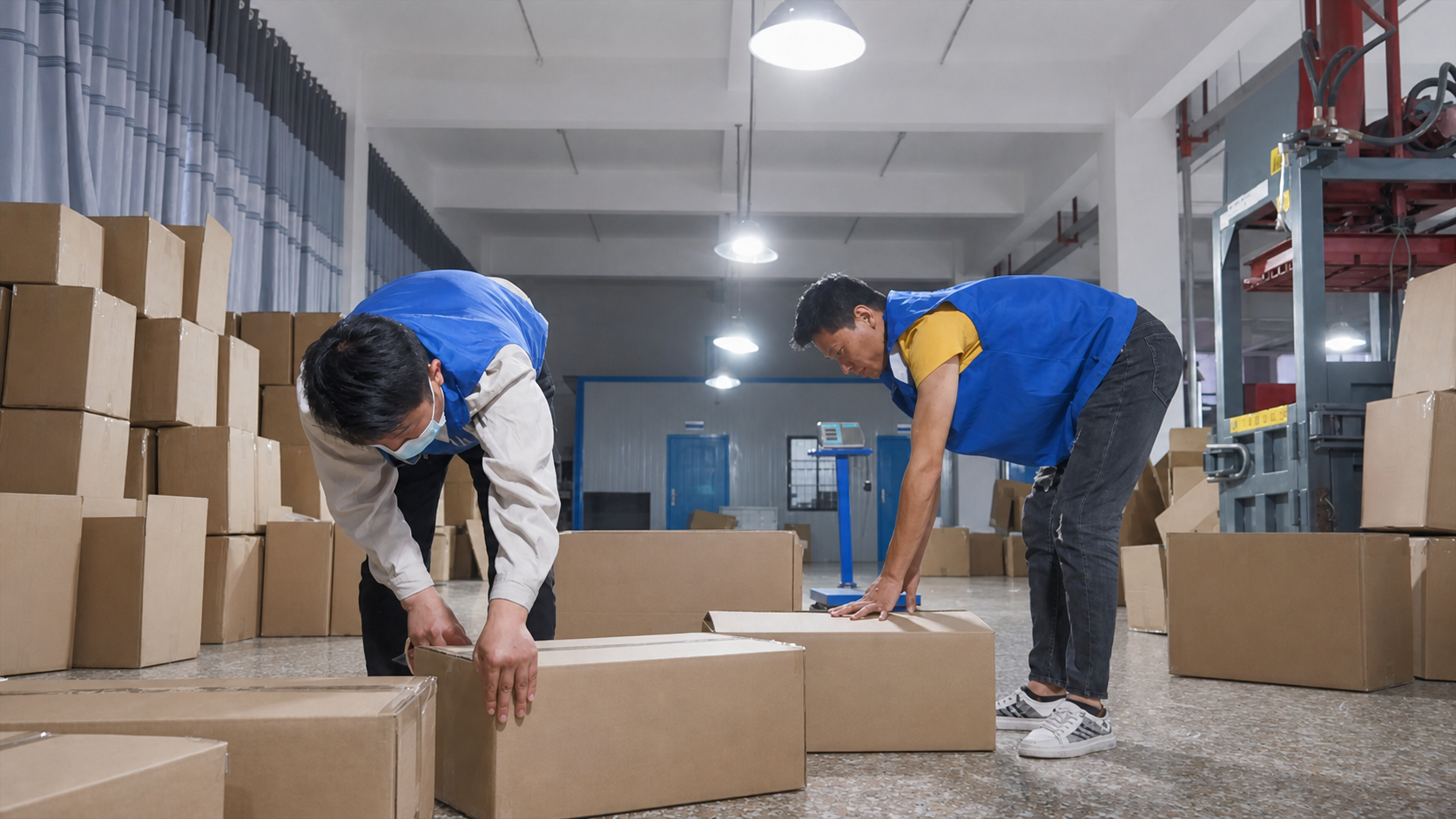 Two workers sealing cartons in a factory packing area