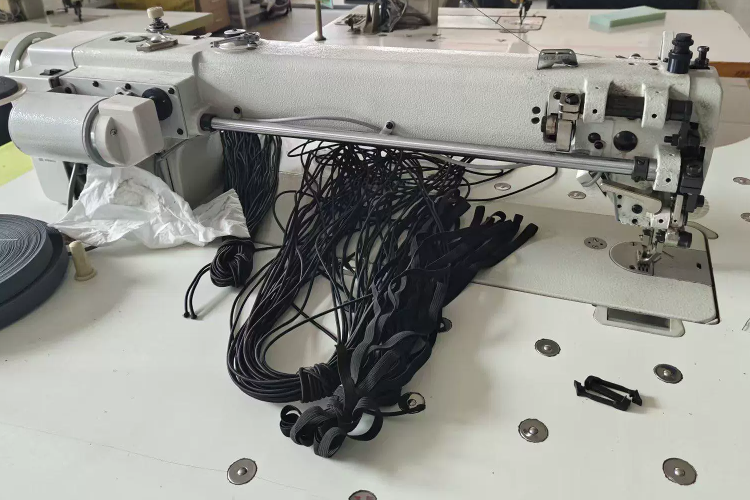 Industrial sewing machine prepared with black cord and webbing components for bag assembly